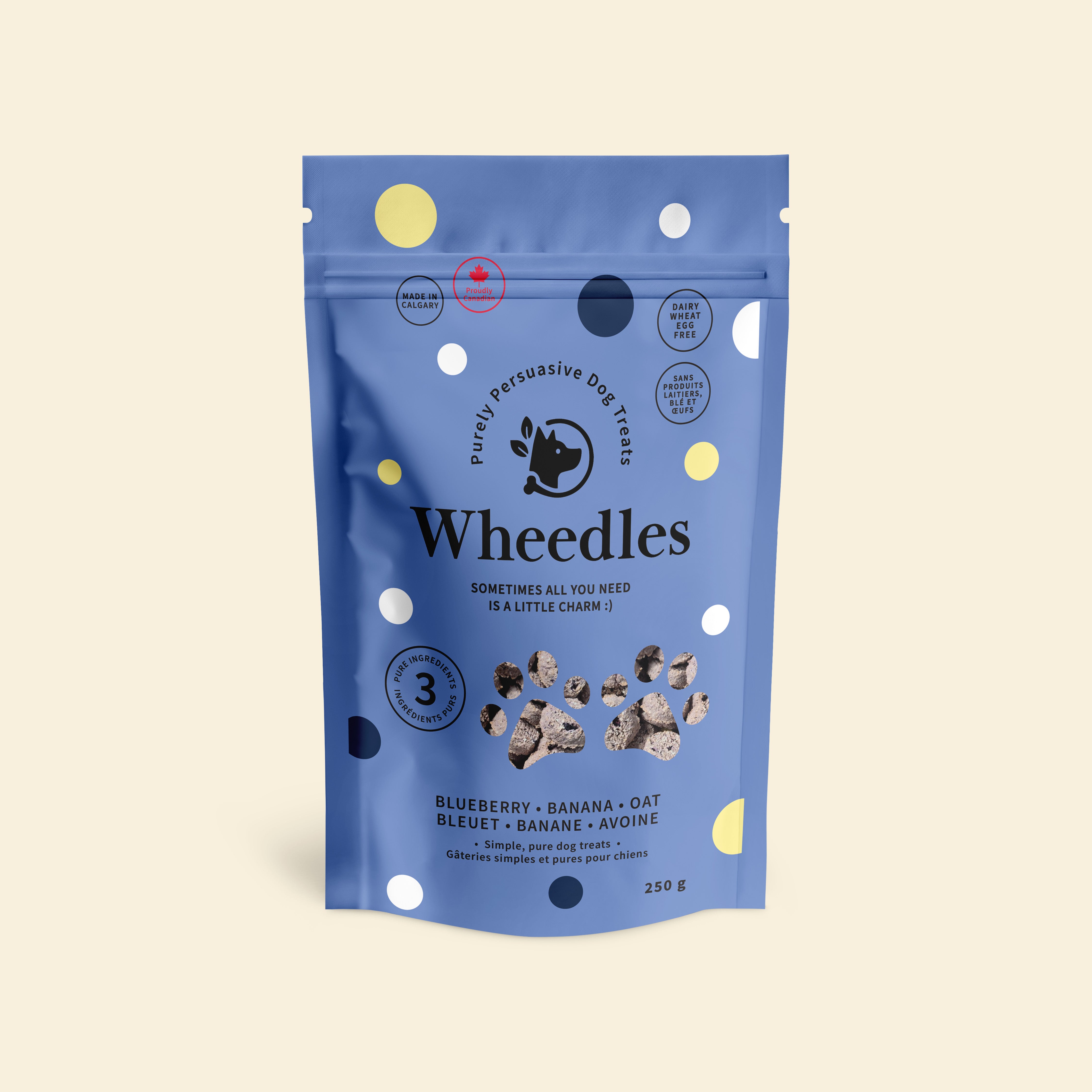 A blue stand-up pouch of Wheedles dog treats banana and blueberry flavour, on a light cream background. The packaging features white, yellow, and dark blue polka dots, with the Wheedles brand name and a paw print logo in the center.